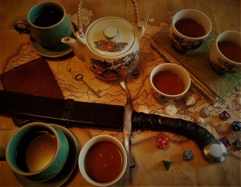 A sword, a teapot, several cups of tea, a couple of bound books, a handful of polyhedral dice, some small shells, and an antique key lie scattered over a map of Skyrim.